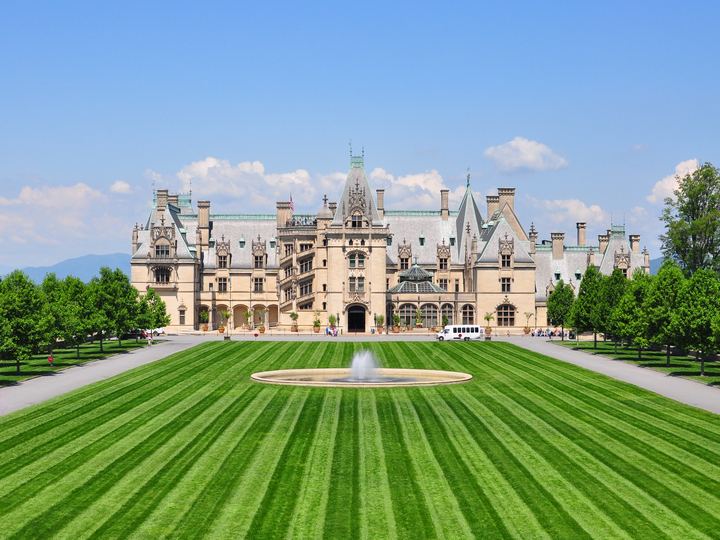 Biltmore House, a vast stone château, seen across a long striped lawn and fountain
