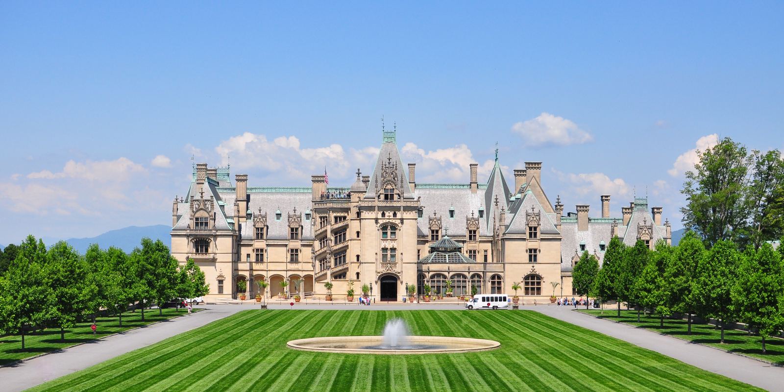 Biltmore House, a vast stone château, seen across a long striped lawn and fountain