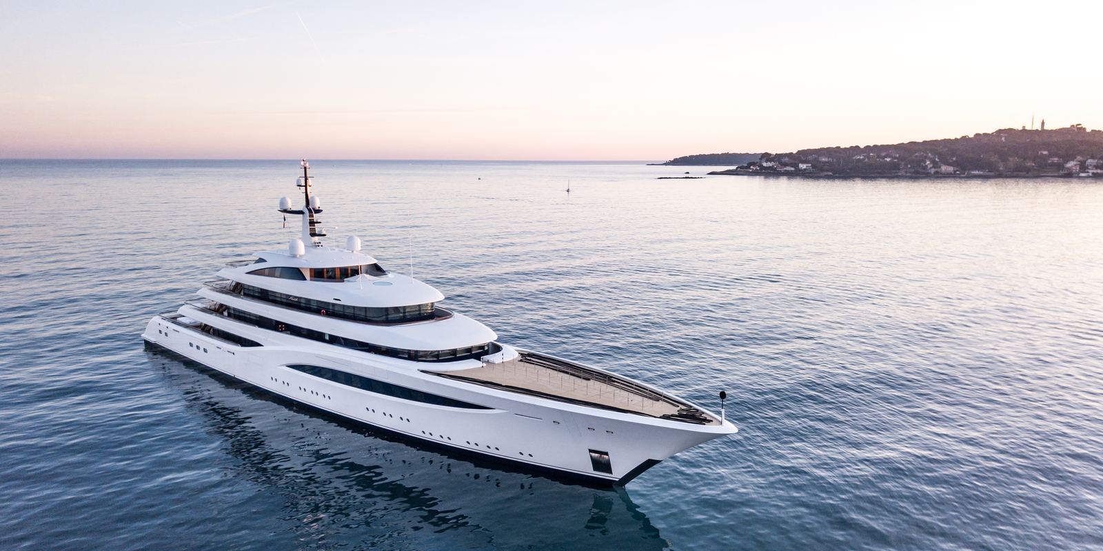 The white Feadship motor yacht Faith cruising on calm water at sunset