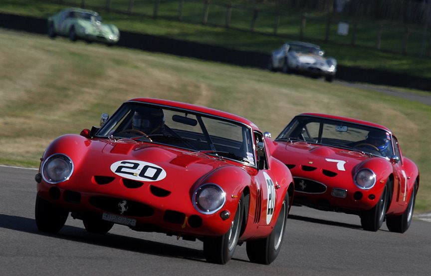 Two red Ferrari 250 GTOs racing at the Goodwood Revival