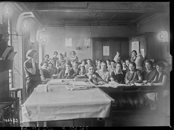 A black and white photograph from 1926 of seamstresses seated around a long worktable in the Paquin atelier