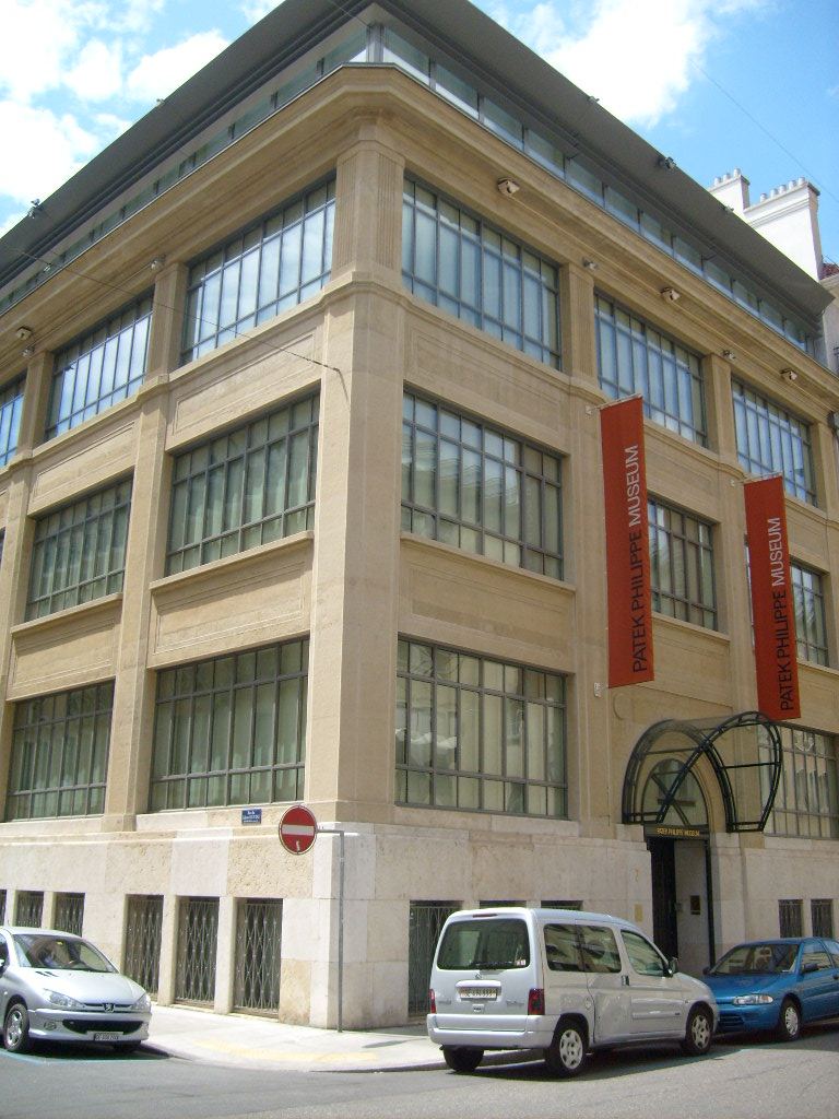 The Patek Philippe Museum building in Geneva with its tall windows and red banners