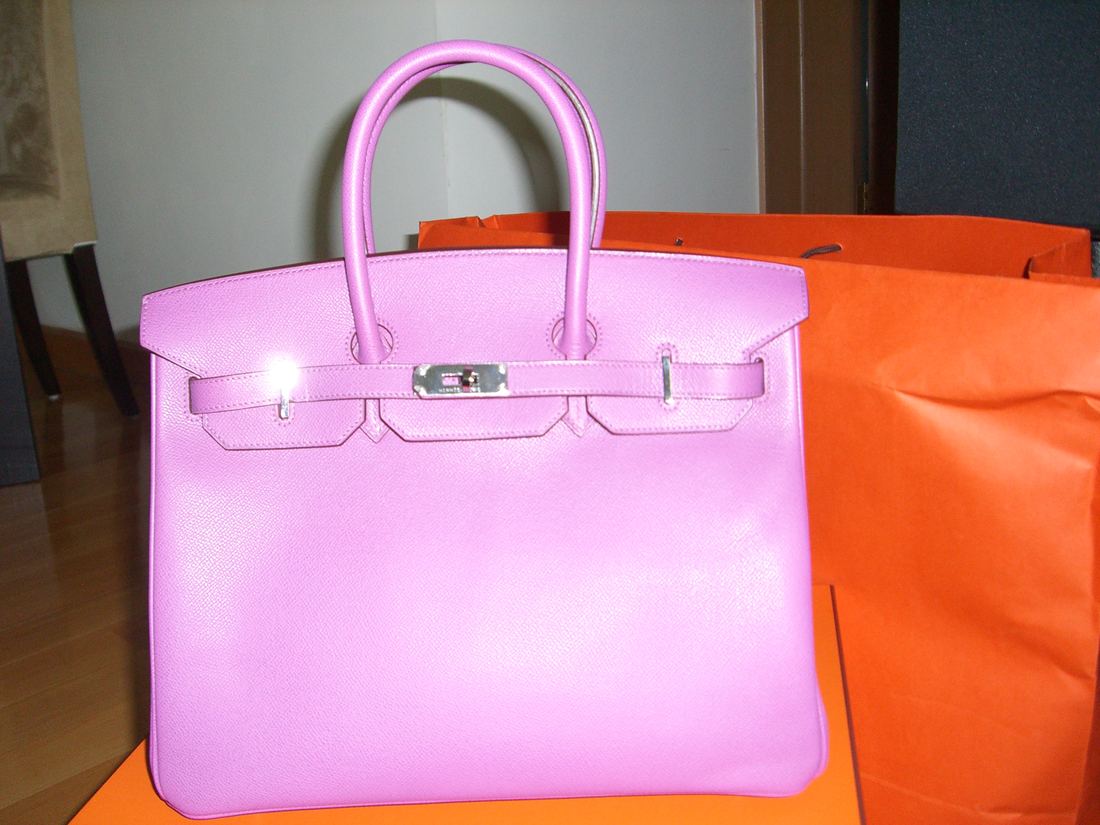A pink leather Hermès Birkin bag resting on an orange box
