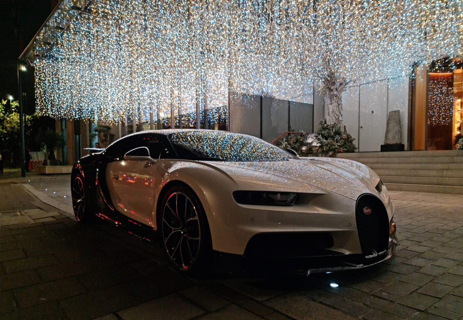 A Bugatti Chiron hypercar parked under a canopy of tiny white lights at night