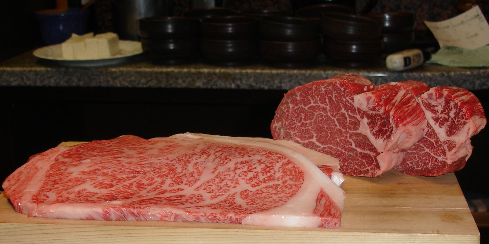 Thick slices of richly marbled Kobe beef on a wooden board