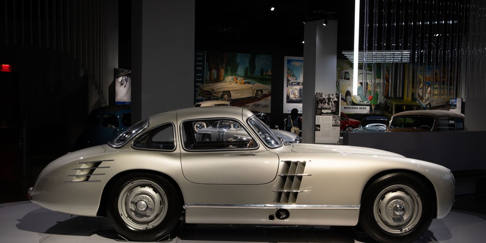 A silver Mercedes-Benz 300 SLR Uhlenhaut Coupe with gullwing doors closed, on display in a museum