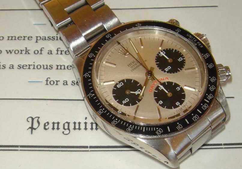 A vintage steel Rolex Cosmograph Daytona lying on an open book